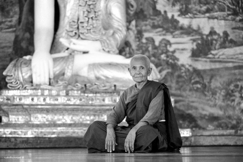 Ein Mönch vor einer Buddha Statue