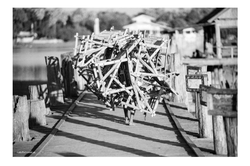 Ein Arbeiter trägt Stühle aus Bambus über eine Brücke