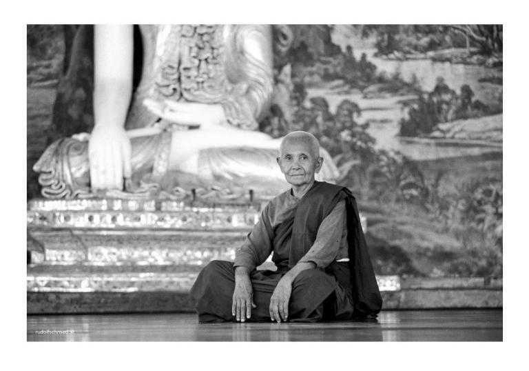 Ein Mönch vor einer Buddha Statue