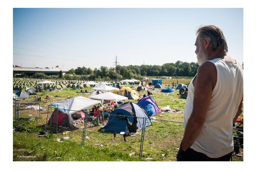 Ein älterer Mann beobachtet einen Campingplatz bei einem Musikfestival